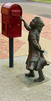 statue of girl posting letter into red street mailbox